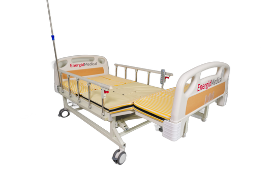 An EnergyMedica L4 adjustable hospital bed with a beige mattress, side rails, and an attached IV pole, shown on a solid white background.